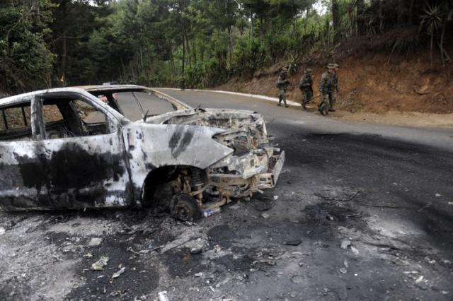 En la carretera que conduce a la laguna El Pito, en Mataquescuintla (Jalapa), fueron quemados tres carros de la Policía Nacional Civil en la noche del lunes. Foto Johan Ordóñez (AFP)﻿.