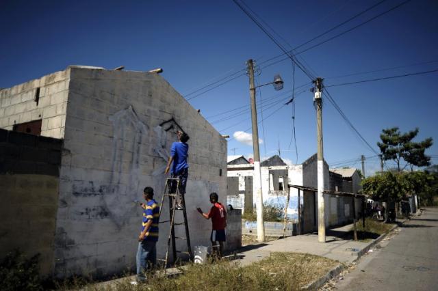 Integrantes del Barrio 18 borran los grafitos alusivos a su pandilla en una campaña de limpieza realizada en enero de 2013. Según los promotores de la tregua, en esta colonia no hay homicidios desde hace 16 meses. Foto José Cabezas (AFP)﻿.
﻿