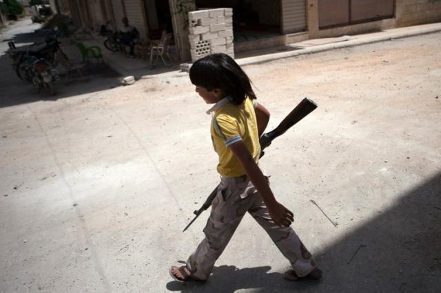 Un niño sirio integrado en el batallón Mártires de Maaret-al-Numan camina con un viejo rifle. La guerra civil inició en enero de 2011. Foto archivo El Faro.