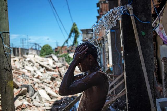 Leandro Souza, de 16 años, toma una ducha junto a las casas demolidas este martes 8 de enero en las inmediaciones del estadio de Maracaná, con motivo del Mundial de fútbol 2014. Foto Yasuyoshi Chiba (AFP).