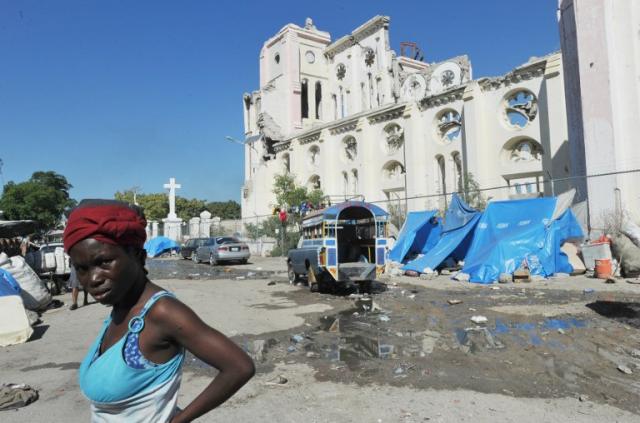 Una haitiana camina este 11 de enero de 2014 frente al esqueleto de la catedral de la capital, Puerto Príncipe. Cuatro años después de la tragedia ni siquiera este emblemático edificio ha sido reconstruido. Foto Thony Belizaire (AFP).