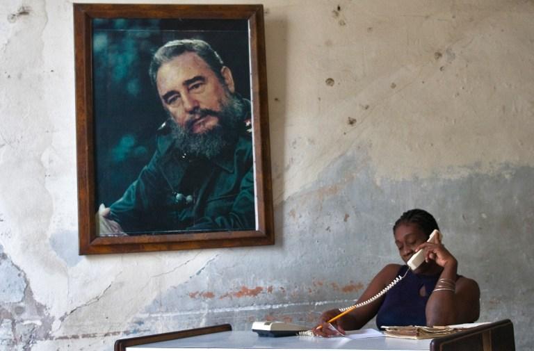 Imagen tomada en agosto de 2009, en la que se ve a una mujer cubana en su oficina gubermamental, a la par de una gran retrato de Fidel Castro. Foto AFP.