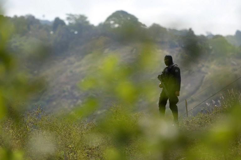Un Agentes de la PNC  hace guardia en los alrededores de la finca San Blas en donde murieron ocho personas, en la madrugada del 26 de marzo de 2015. Foto: AFP