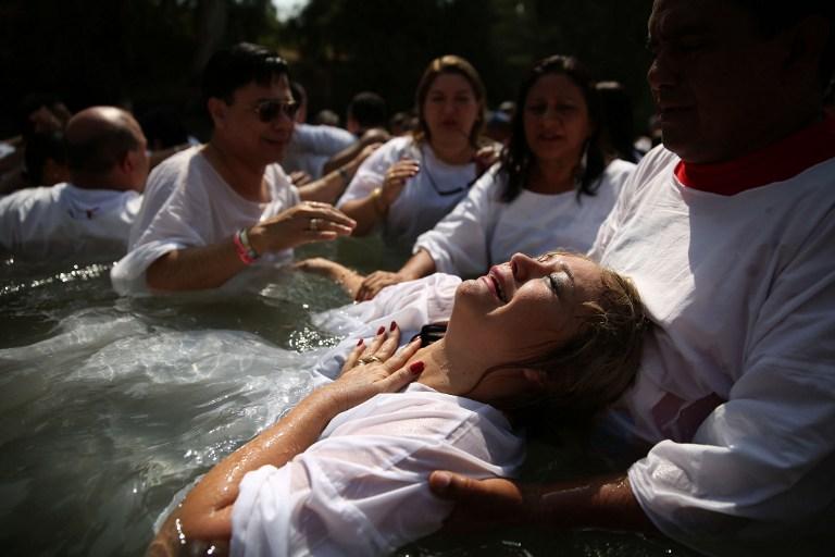 Un grupo de peregrinos evangélicos brasileños se bautiza en las aguas del río Jordan, en Israel, donde los creyentes aseguran que fue bautizado Jesucristo. Foto Gali Tibbon (AFP).