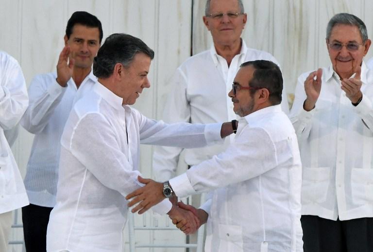 El presidente de Colombia Juan Manuel Santos (izquierda) y el líder de la guerrilla de las FARC Timoleon Jimenez, alias Timochenko, se dan un apretón de manos durante la firma del histórico acuerdo de paz entre el gobierno y el grupo rebelde. AFP PHOTO / Luis ACOSTA