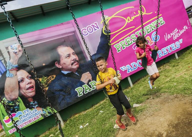 Niños se divierten en el parque Adolfo Reyes de Managua, frente a un cartel promocional de Daniel Ortega  y Rosario Murillo, candidatos a presidente y vicepresidenta por el FSLN en las elecciones presidenciales que Nicaragua celebrará el próximo 6 de noviembre. Foto Inti Ocón (AFP).