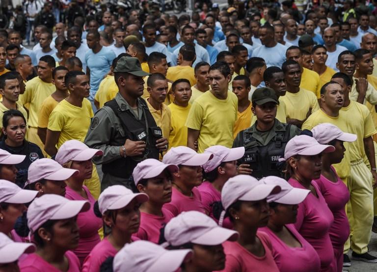 Members of the National Guard custody inmates whose identity was, according to the government, missappropiated by the opposition to sign a recall referendum against Venezuelan President Nicolas Maduro, outside the Public Ministry building in downtown Caracas on June 17, 2016. / AFP PHOTO / JUAN BARRETO