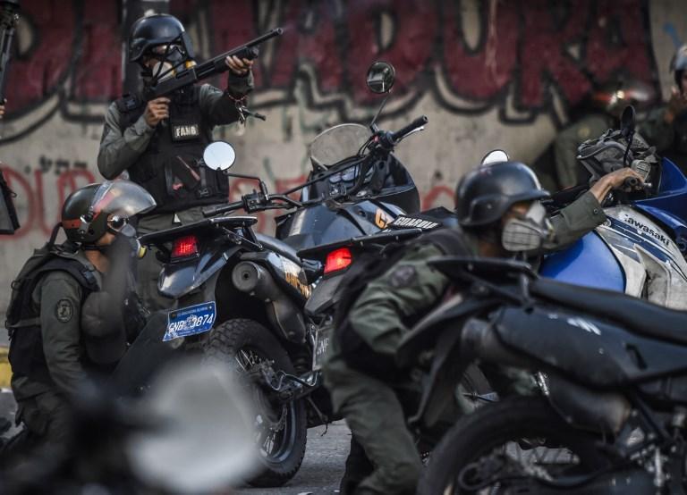 Motociclistas de la Guardia Nacional Bolivariana (GNB) se cubren de disparos durante las protestas en Caracas, este 30 de julio, en la jornada de elección de la polémica Asamblea Constituyente. Foto Juan Barreto (AFP).
