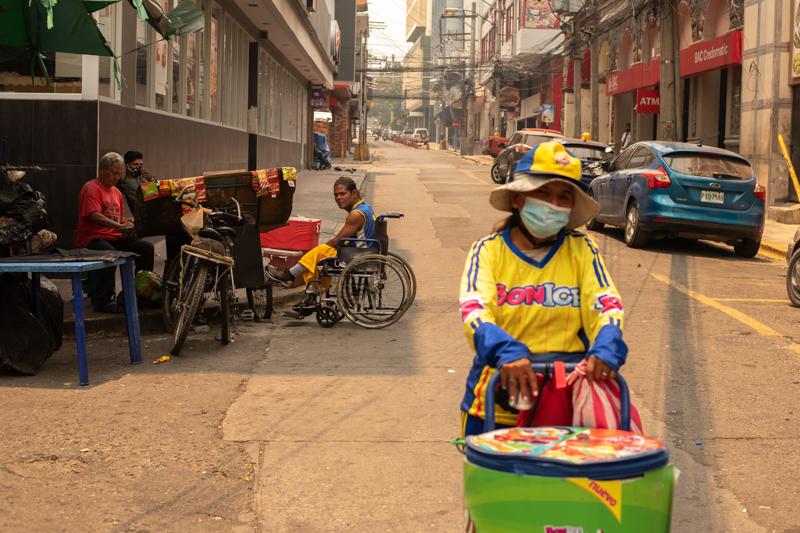 A woman selling ice cream walks down a once-bustling downtown street--now empty due to the lockdown. San Pedro Sula. April, 17th, 2020. Photo: Seth Berry