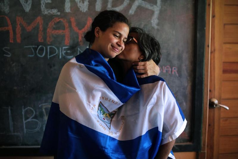 Student activist Amaya Coppens (left) is kissed by her mother while wrapped in the Nicaraguan flag. Coppens was jailed for protesting Ortega