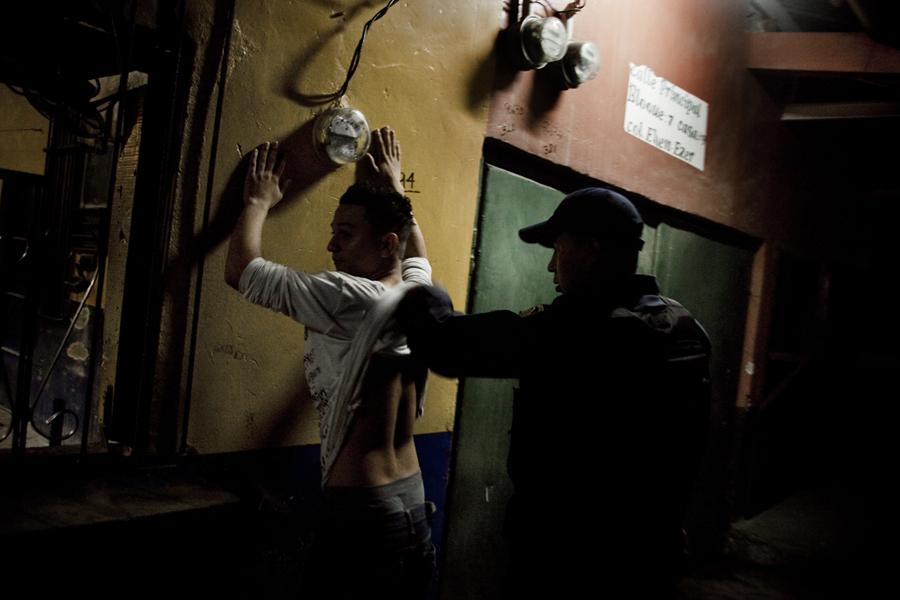 Un agente de la Policía Nacional registra a un cliente de un billar situado en las afueras de San Pedro Sula, durante un operativo especial para buscar armas. Según cifras oficiales, en 2015 murieron asesinados 844 hondureños menos que en 2014. Foto archivo El Faro.