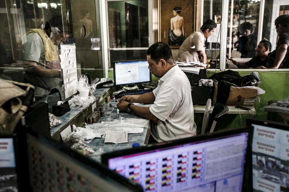 One of Catalino Miranda’s employees counting money in a bus terminal in San Salvador. Fred Ramos/El Faro for The New York Times